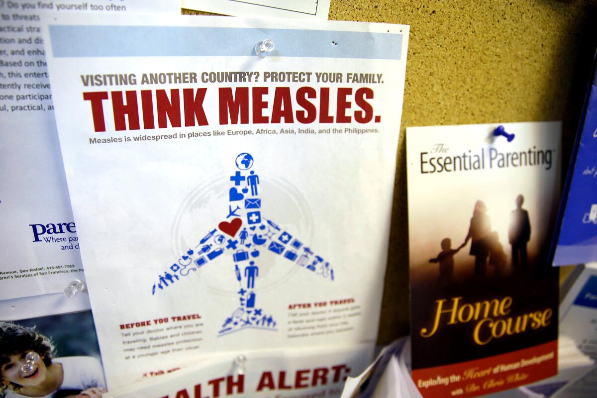An instructional flier about measles is pinned to a bulletin board that reads "Think Measles" above a plane illustration.