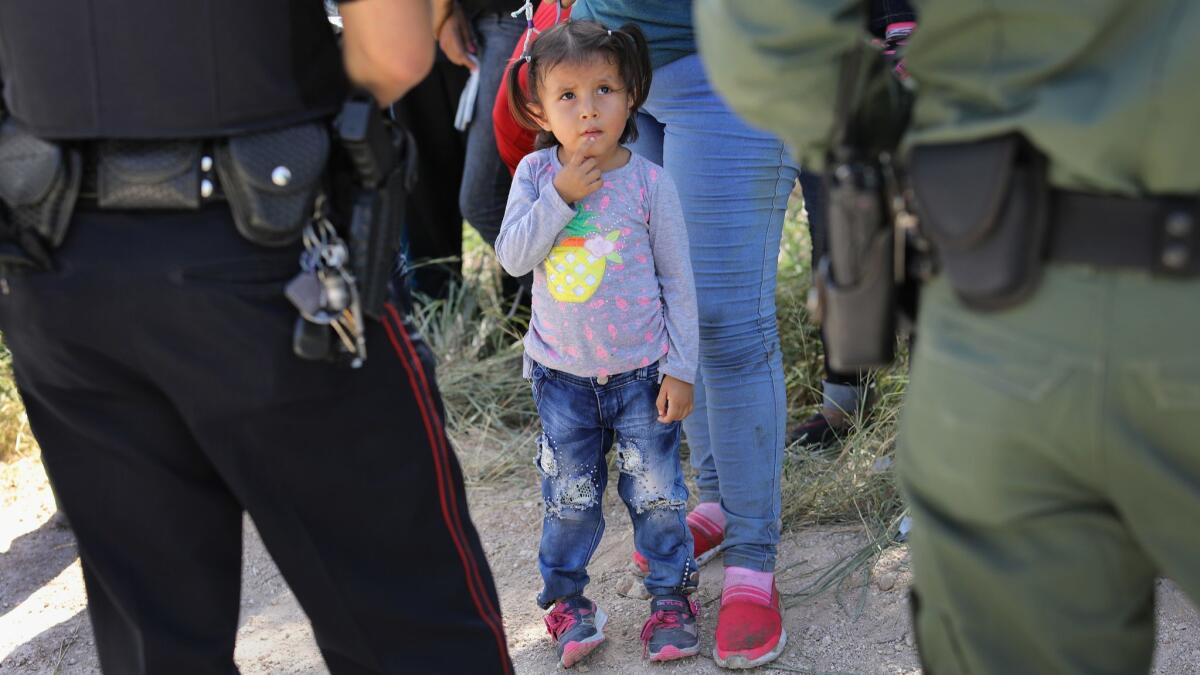 A police officer and Border Patrol agent watch over a group of Central American asylum seekers before taking them into custody near McAllen, Texas.