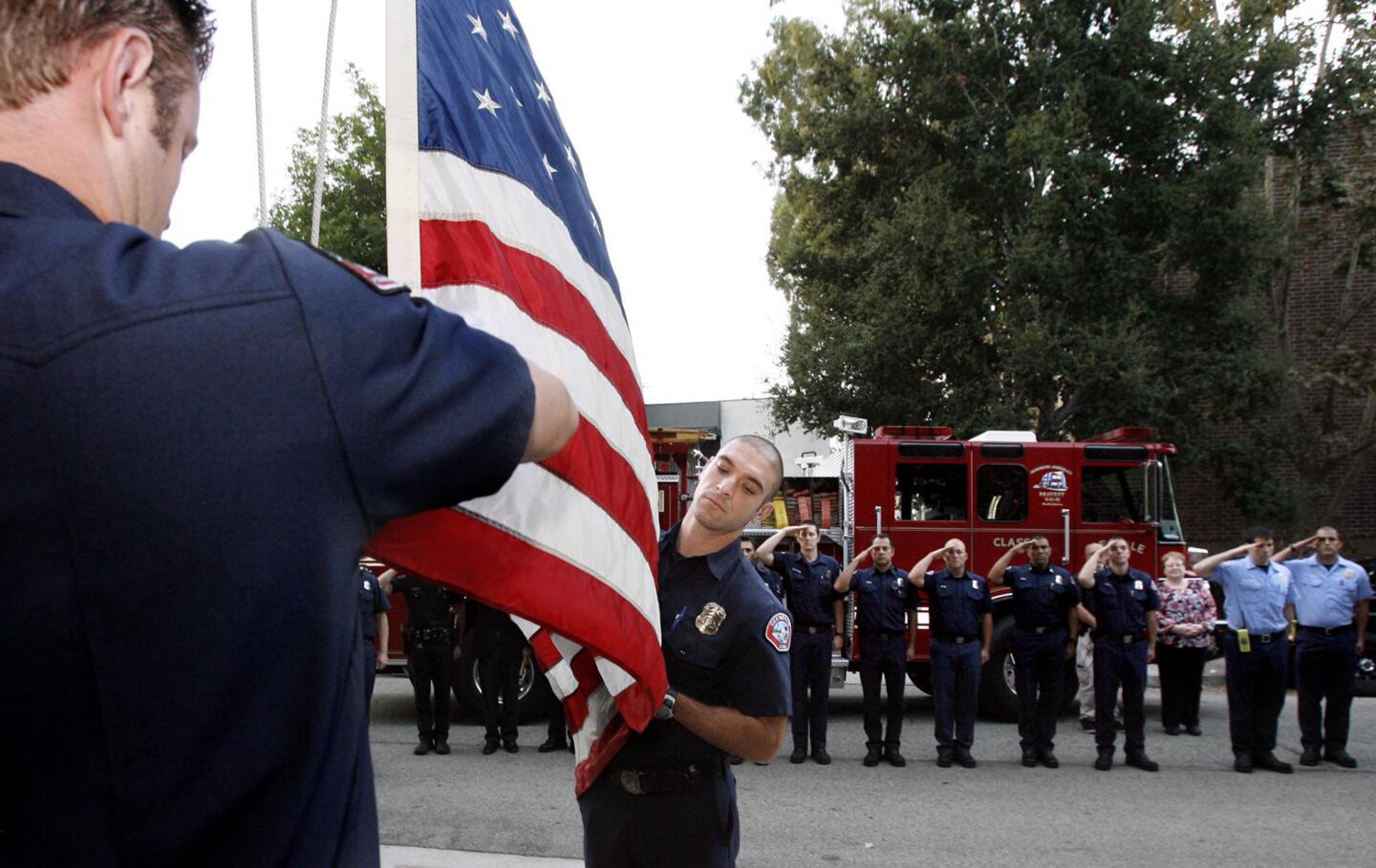 Glendale Fire Station 21 firefighters Andrew Gano, left, and Ara Hoonanian, right, raise Old Glory during 911 ceremony at Station 21 on Tuesday, Sept. 11, 2012. The ceremony, where some names of victims were read by GFD and Glendale Police, was done to commemorate those who died on Sept. 11 2001 in attacks in New York City, The Pentagon and Pennsylvania.