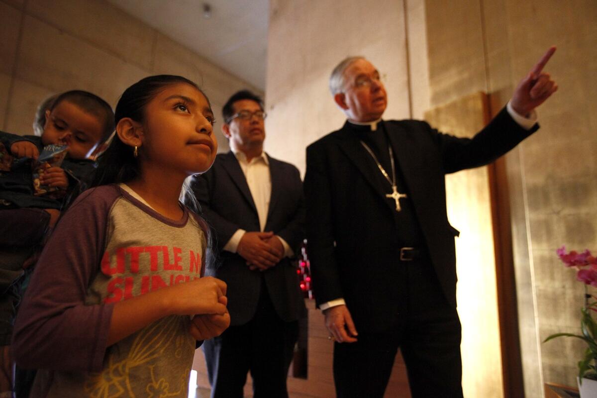 Los Angeles Archbishop Jose Gomez, right, shows Zeya Vargas, 2, left, his sister Jersey Vargas, 10, center, and Juan Jose Gutierrez of the Full Rights for Immigrants Coalition the chapel of Our Lady of Guadalupe.