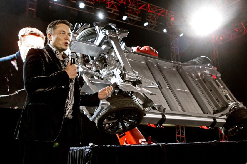 Elon Musk shows off the undercarriage of a Tesla auto in this 2014 file photo. But what's under the hood of his offer for SolarCity?