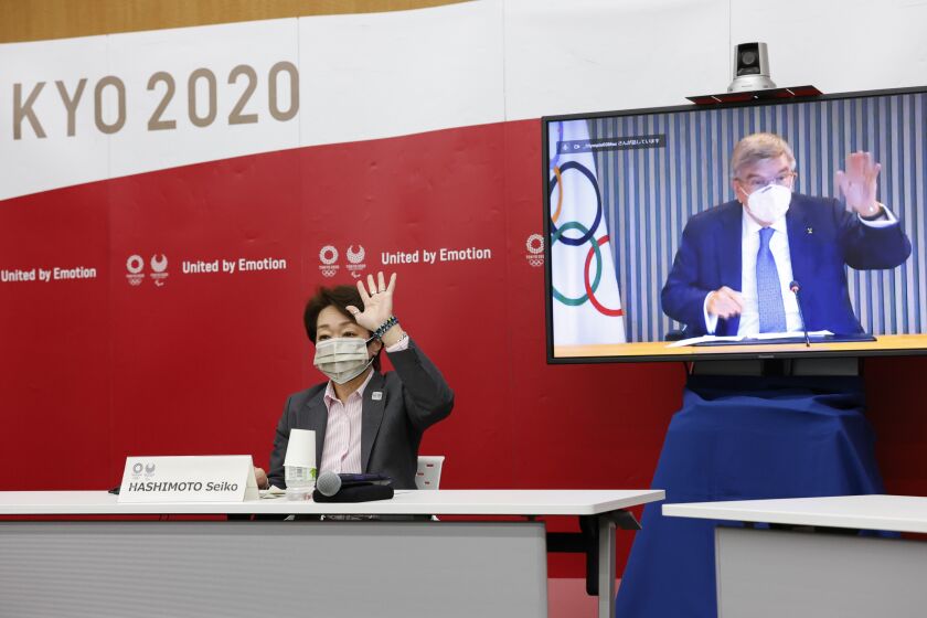 Tokyo 2020 President Seiko Hashimoto and IOC President Thomas Bach, on a screen, greet each other during a five-party online meeting at Harumi Island Triton Square Tower Y in Tokyo Monday, June 21, 2021. The Tokyo Olympics will allow some local fans to attend when the games open in just over a month, Tokyo organizing committee officials and the IOC said on Monday. (Rodrigo Reyes Marin/Pool Photo via AP)