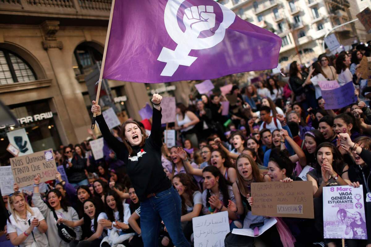A woman waves a feminist flag as student protesters shout slogans during a demonstration marking International Women's Day in Barcelona, Spain.