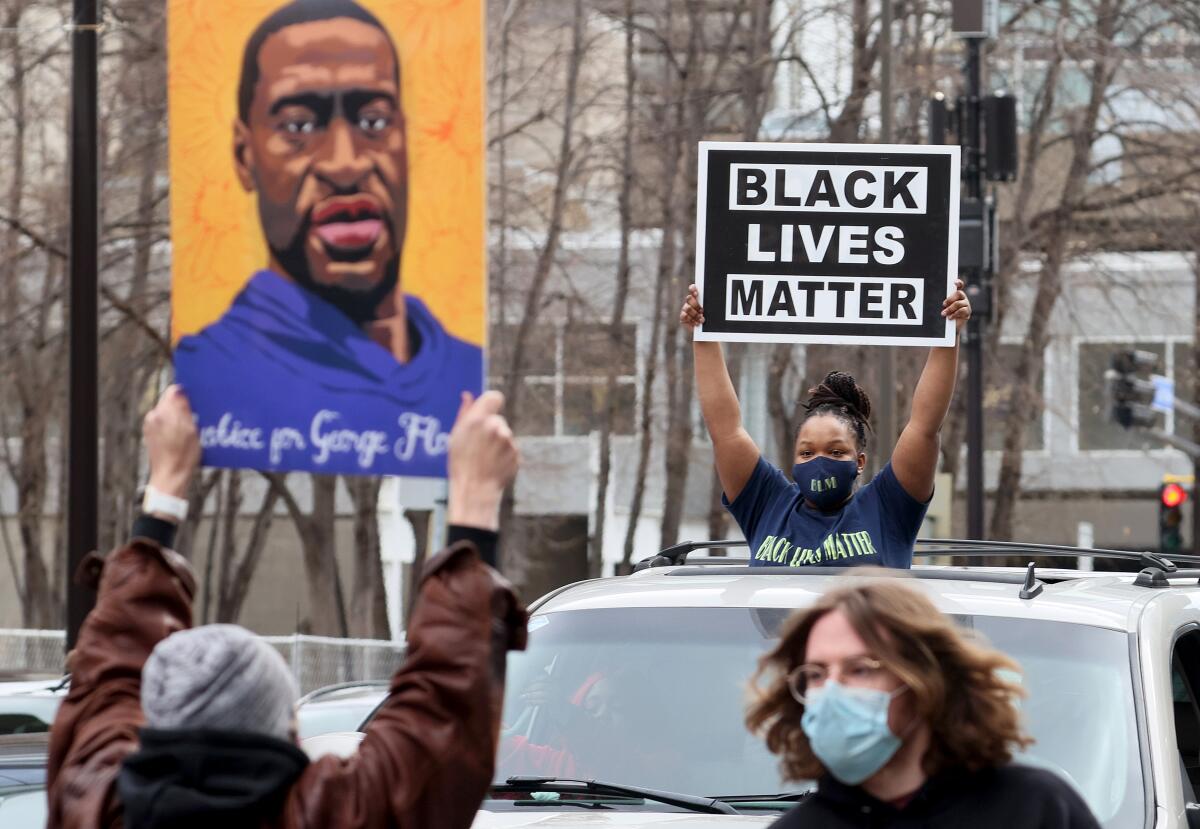 In cars and on the street, people hold signs reading Black Lives Matter and showing George Floyd's face 