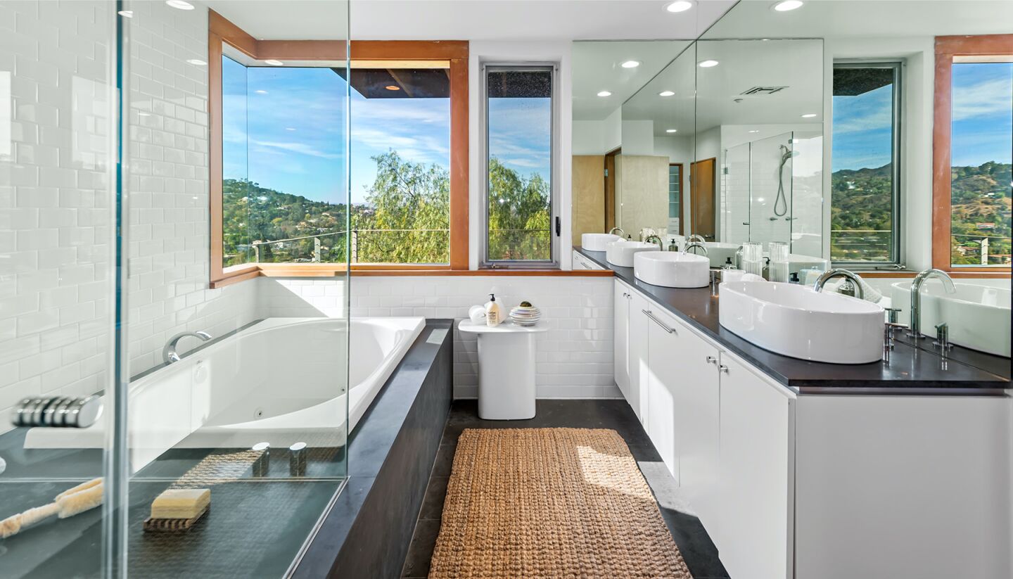 The bathroom has a raised sink, bath tub and window views of the hills.