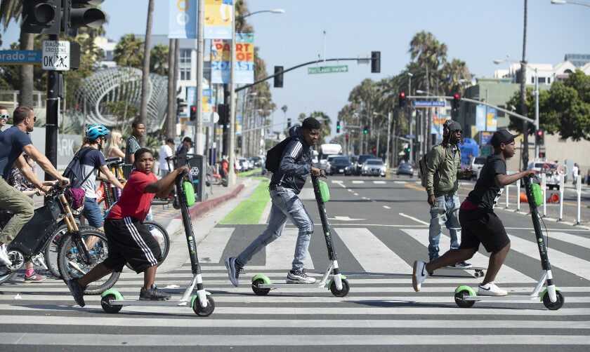 People on lime scooters in a pedestrian crossing in Santa Monica