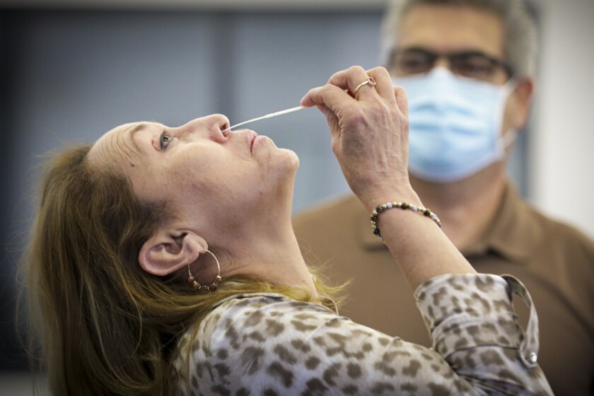 A woman swabs her nose for a coronavirus test