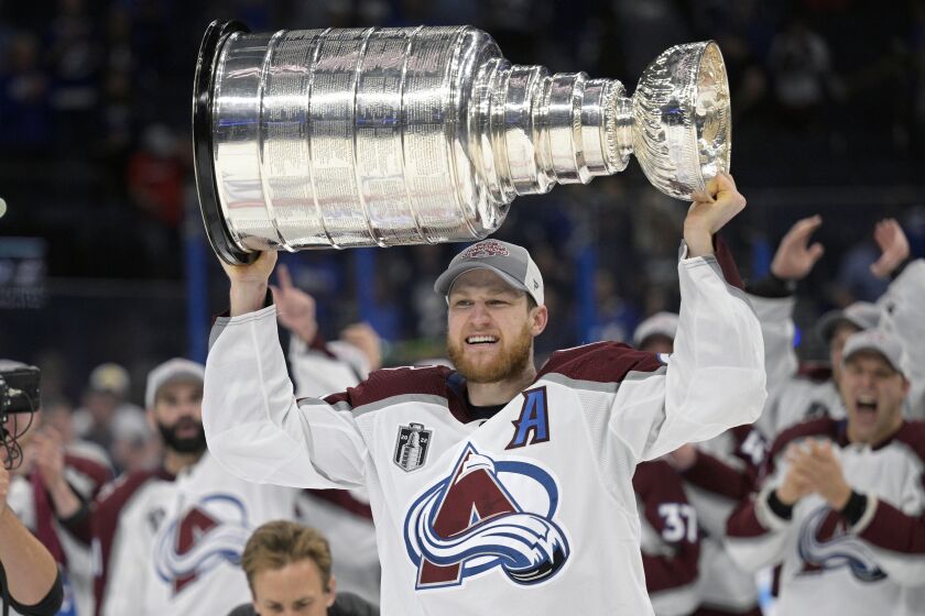 FILE - Colorado Avalanche center Nathan MacKinnon lifts the Stanley Cup after the team defeated the Tampa Bay Lightning in Game 6 of the NHL hockey Stanley Cup Finals on Sunday, June 26, 2022, in Tampa, Fla. MacKinnon will be wearing the burgundy and blue for quite a while after signing an eight-year contract worth $100.8 million. The 27-year-old MacKinnon is coming off a postseason where he tied for the NHL lead with 13 goals. (AP Photo/Phelan M. Ebenhack, File)