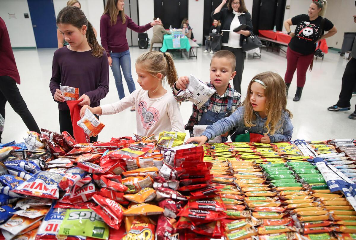 Teagan Noonan, 6, Calvin Schmidt, 4 1/2, and Maren Lee, 5, center from left, help fill stockings.