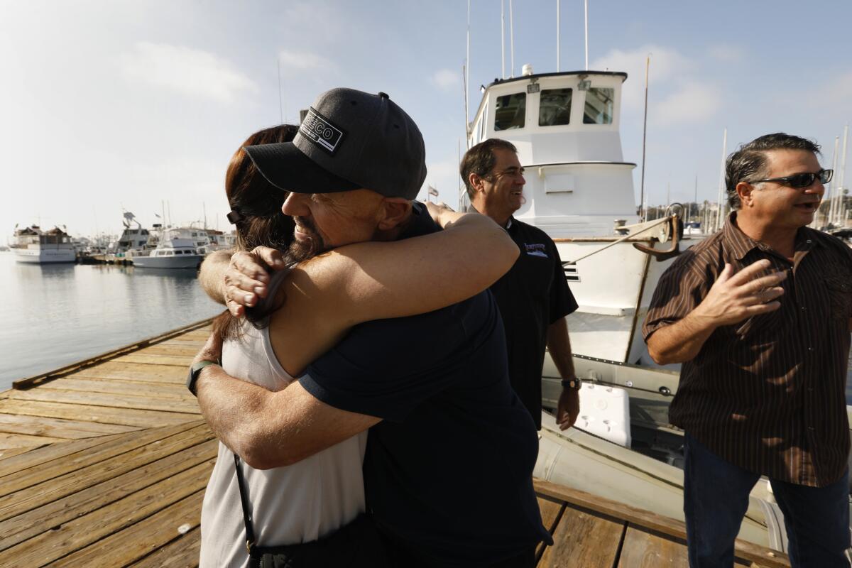 Two people hug on a pier.