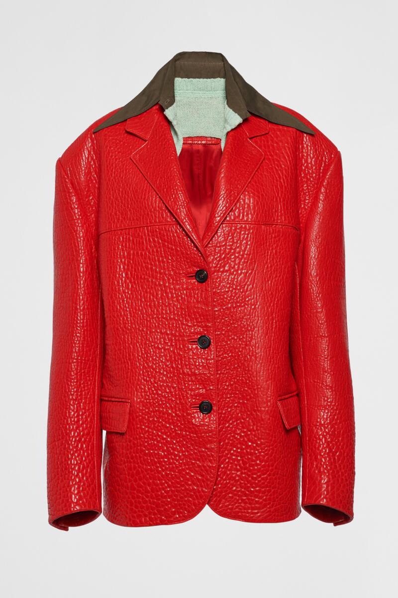 Prada’s electric, bright red leather jacket hangs on a hanger
