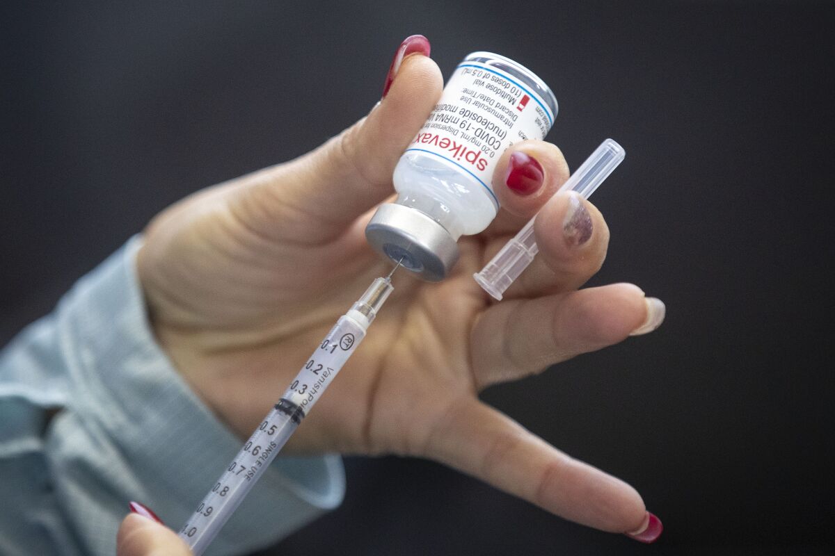A person draws out Moderna vaccine during a drive through COVID-19 vaccine clinic at St. Lawrence College in Kingston, Ontario, on Sunday Jan. 2, 2022. (Lars Hagberg /The Canadian Press via AP)