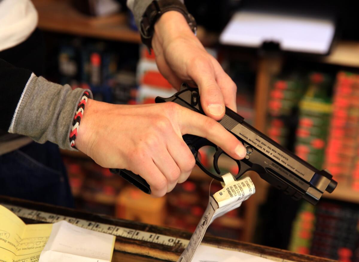 A gun shop employee in Tinley Park, Ill., outside Chicago, shows a Beretta 9mm handgun in 2014.