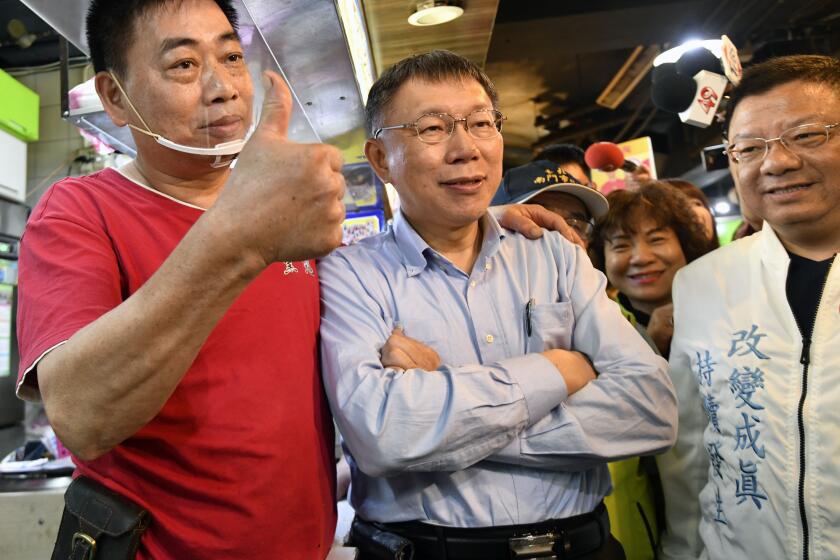 This picture taken on November 9, 2018 shows independent Taipei mayor candidate Ko Wen-je (C) posing for photos with a supporter (L) during the elections campaign at a traditional market in Taipei. - When Taiwan goes to the polls on November 24, 2018 in local elections, it will not only be a test for President Tsai Ing-wen's embattled government but a crucial vote on divisive issues that could rile China. (Photo by SAM YEH / AFP) / TO GO WITH STORY: Taiwan-China-vote-referendum-politics, ADVANCER by Amber WANG (Photo credit should read SAM YEH/AFP via Getty Images)