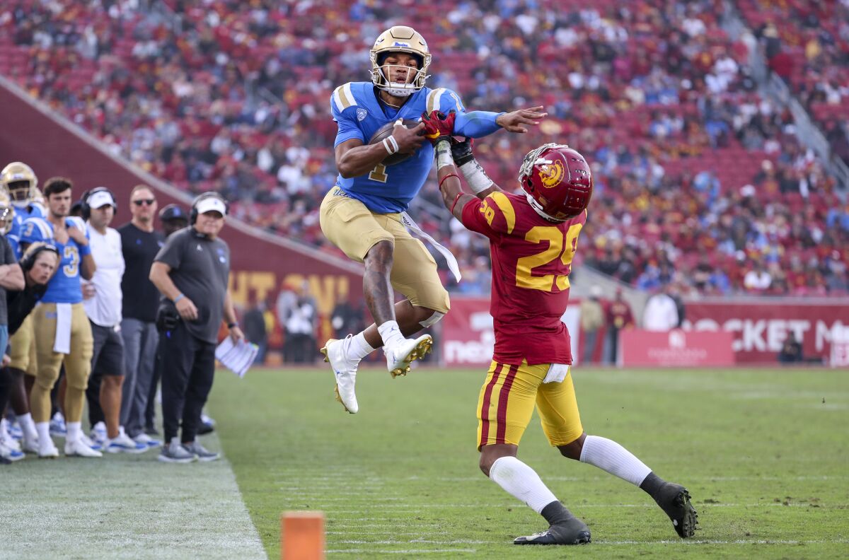 UCLA quarterback Dorian Thompson-Robinson, left, leaps in attempting to get past USC safety Xavion Alford