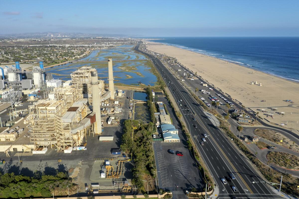 Aerial view of a power plant next to wetlands and a roadway by the beach