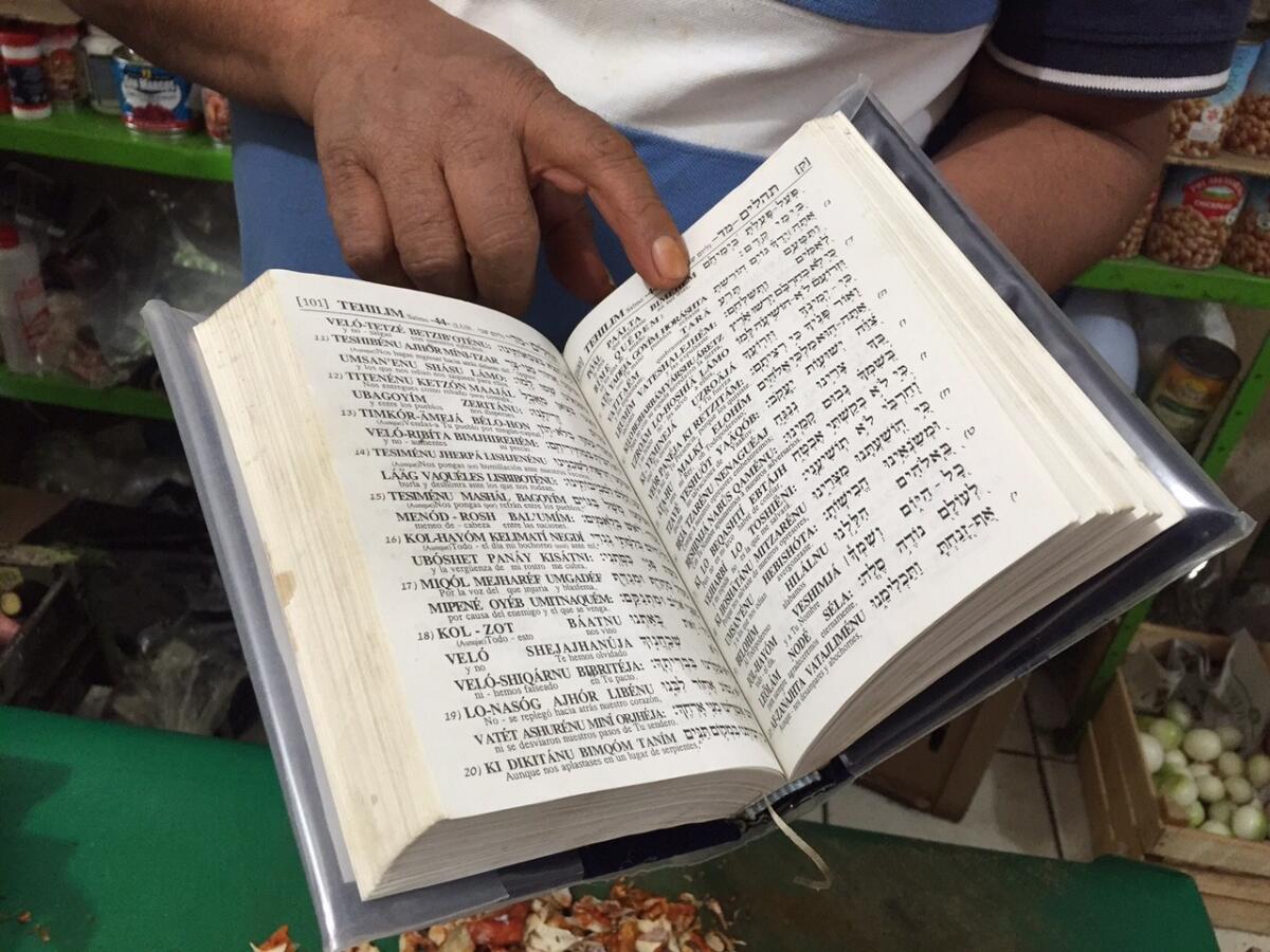 Noe Trinidad Chavez displays a Book of Psalms in Hebrew and Spanish. It was a gift from one of his many Jewish customers.