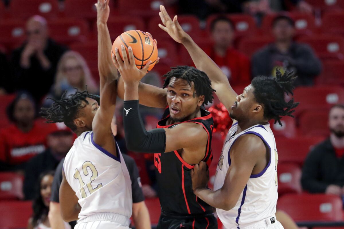 Houston center Josh Carlton, center, looks to pass the ball from between Alcorn State guards Dekedran Thorn (12) and Darius Agnew, right, during the first half of an NCAA college basketball game Monday, Dec. 6, 2021, in Houston. (AP Photo/Michael Wyke)