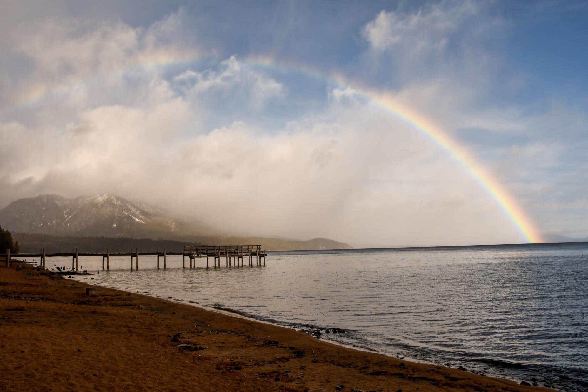 A rainbow arcs across mountains and into the water at Camp Richardson on the south shore of Lake Tahoe.