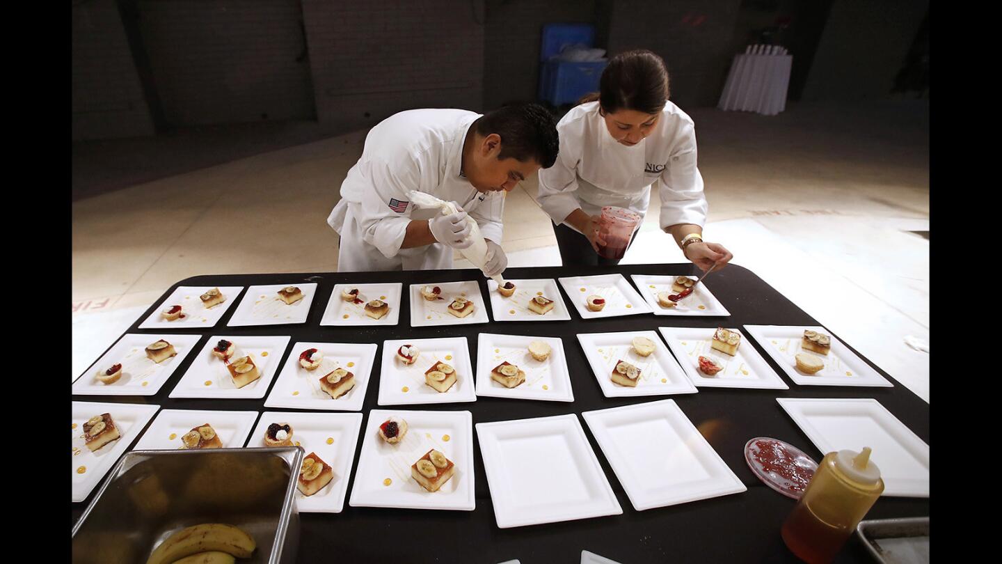 As the crowds arrive, Serafin Cienfuegos, left, and Corey Klass from Nick's restaurant add finishing touches to plates of banana flan and butter cakes during the Taste of Laguna at the Festival of Arts grounds on Thursday.