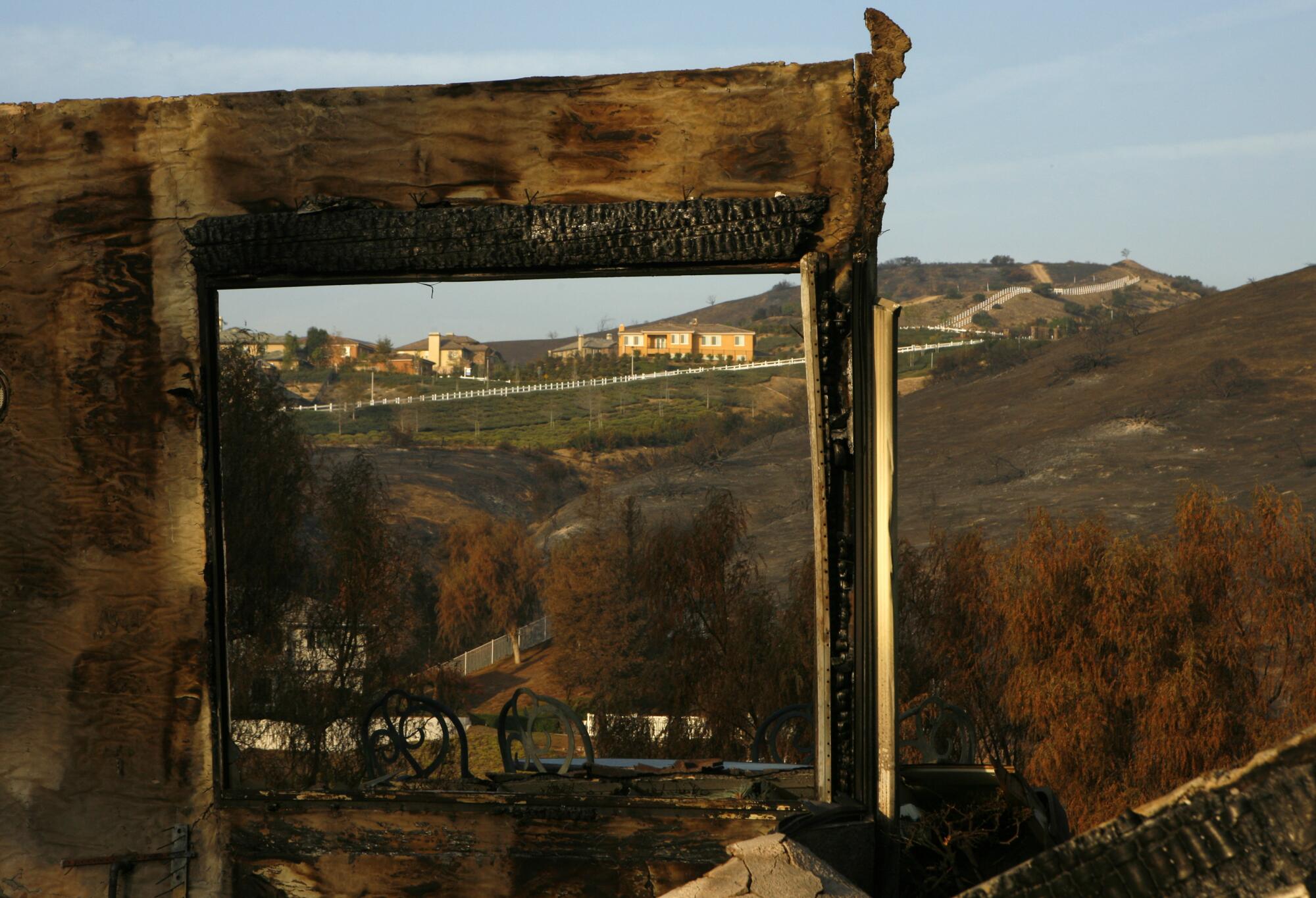 The aftermath of the Freeway Complex fire shows the burned walls of a house in Yorba Linda frame rolling hills.