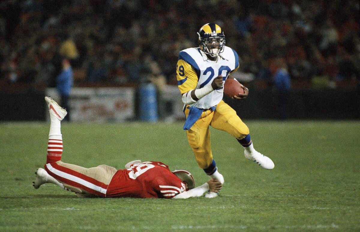 Rams running back Eric Dickerson carries the ball as San Francisco 49ers linebacker Mike Walter tries to tackle him.