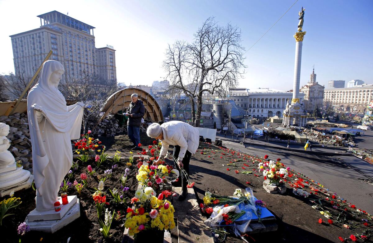 A woman tends a memorial at Independence Square in Kiev for those who gave their lives in the protest that brought down Ukrainian President Viktor Yanukovich.