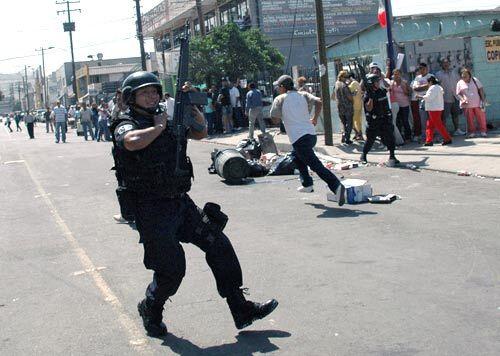 A policeman runs by the La Mesa State Penitentiary in Tijuana, Mexico, where a second riot in three days left at least 17 people dead.