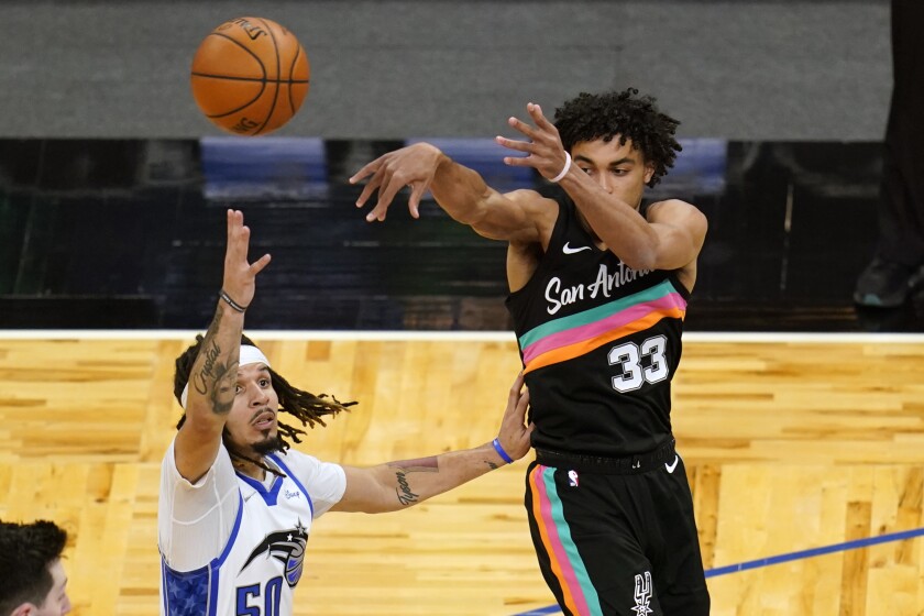 San Antonio Spurs guard Tre Jones (33) passes the ball over Orlando Magic guard Cole Anthony during the second half of an NBA basketball game, Monday, April 12, 2021, in Orlando, Fla. (AP Photo/John Raoux)