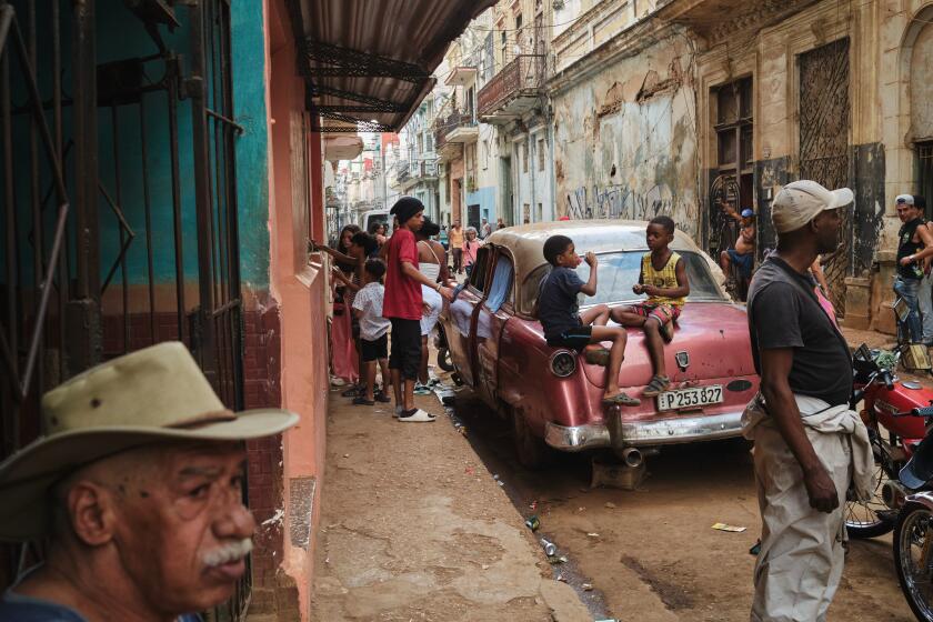 Children play on top of an "almendron" on a busy street in Central Havana, March 1, 2026. (Natalia Favre/For The Times)