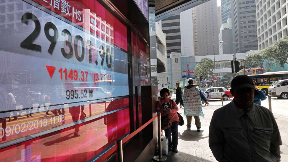 A man passes an electronic board showing a Hong Kong stock index outside a bank on Feb. 9.