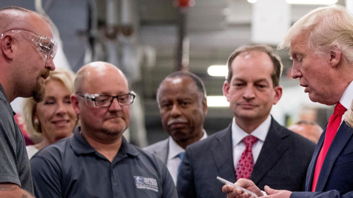 President Donald Trump, accompanied by Labor Secretary Alexander Acosta, second from right, tours Waukesha County Technical College in Pewaukee, Wis., on June 13.