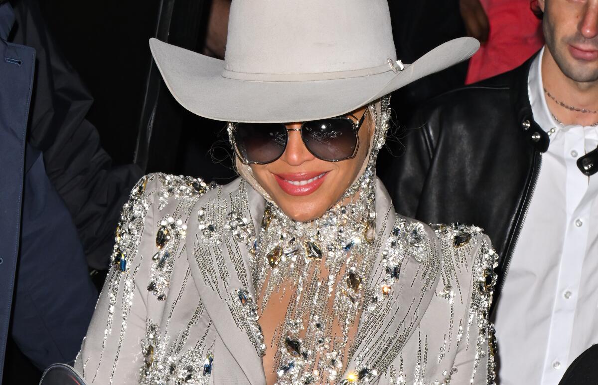 Beyoncé wears a large white cowboy hat, sunglasses and a jeweled blazer to a fashion show
