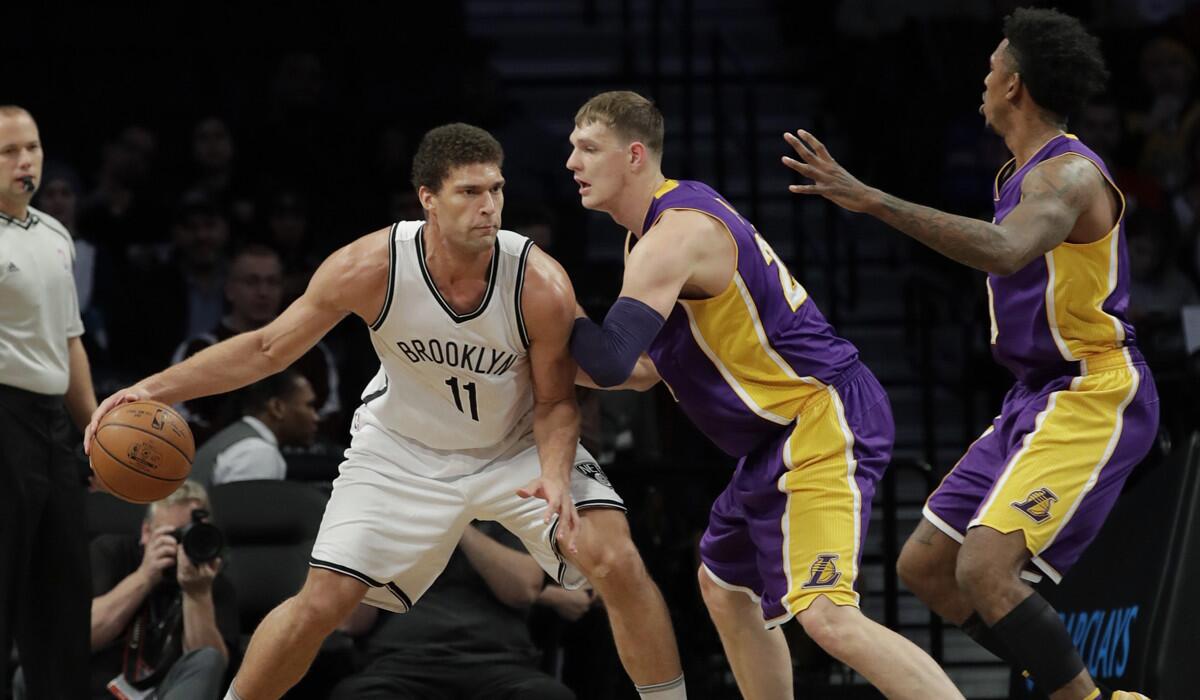 Timofey Mozgov of the Lakers, center, and Nick Young defend Brook Lopez of the Brooklyn Nets in the first half.