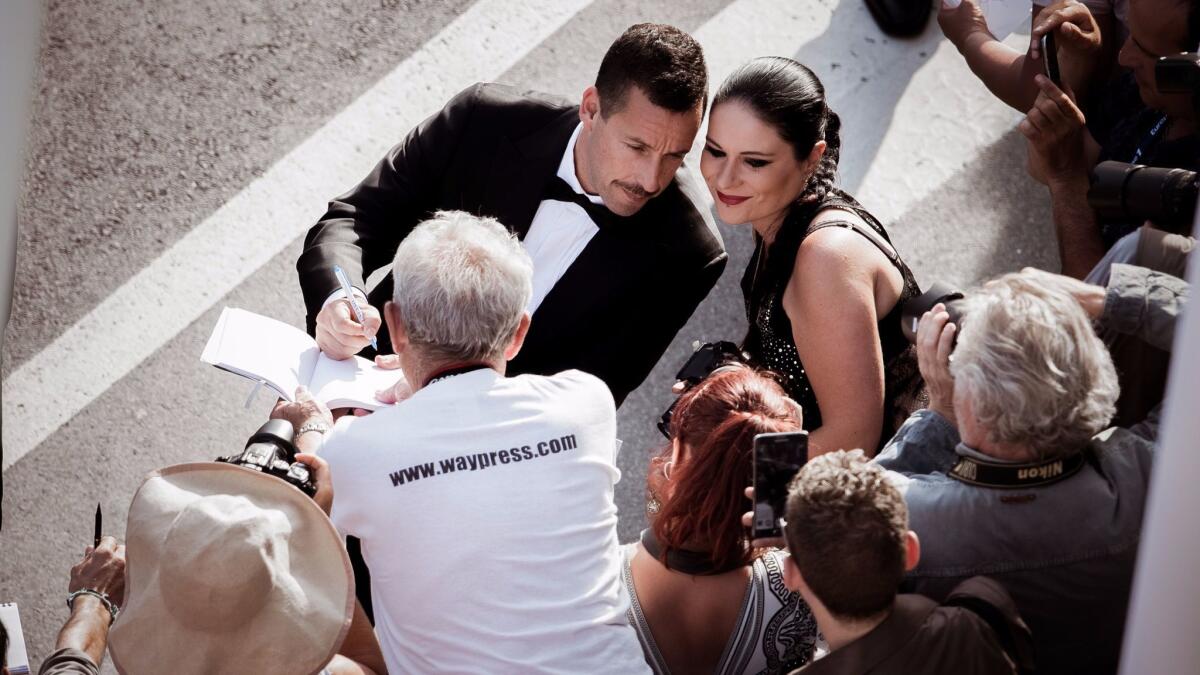Adam Sandler does some Cannes multitasking, signing an autograph and posing for a fan photo outside the screening for his new movie "The Meyerowitz Stories," directed by Noah Baumbach.
