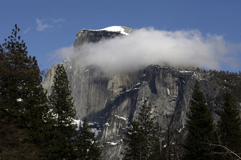 YOSEMITE NATIONAL PARK, CA - APRIL 11: Yosemite Half Dome dusted with snow and clouds on April 11, 2020. Yosemite National Park is closed to visitors due to the coronavirus, Covid 19. Animals roam the park without having to worry about crowds of people. Madera County on Saturday, April 11, 2020 in Yosemite National Park, CA. (Carolyn Cole / Los Angeles Times)