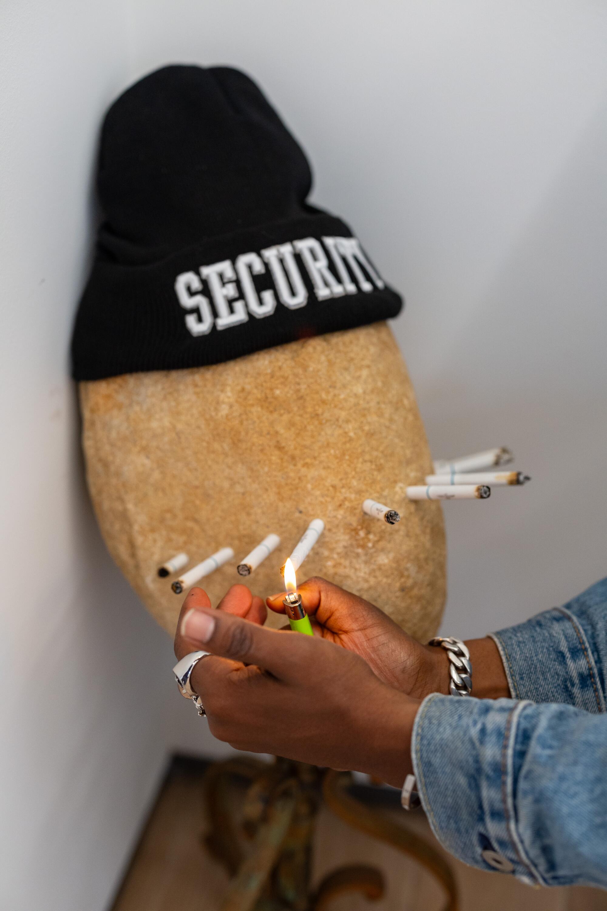 Artist Awol Erizku lights a cigarette that is part of one of his art pieces on exhibit at Sean Kelly gallery.