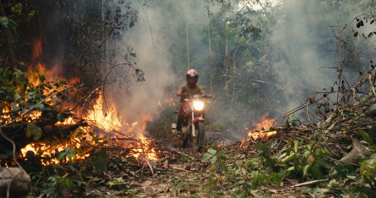 A motorcyclist rides through a burning rainforest in the documentary "The Territory."