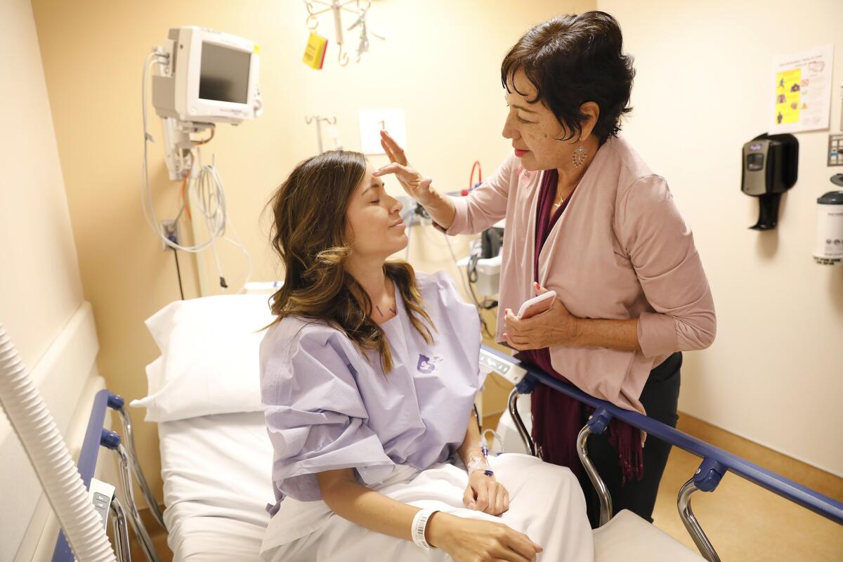 Cecilia Medellin makes the sign of the cross on daughter Alejandra Campoverdi's forehead before her double mastectomy. (Christina House / Los Angeles Times)