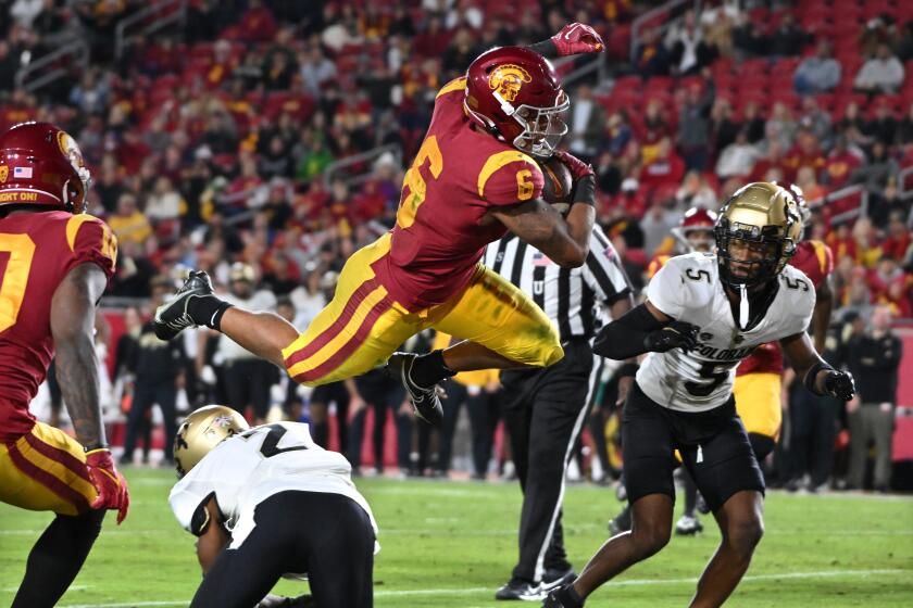 USC running back Austin Jones leaps into the end zone for a touchdown in front of Colorado safety Tyrin Taylor.