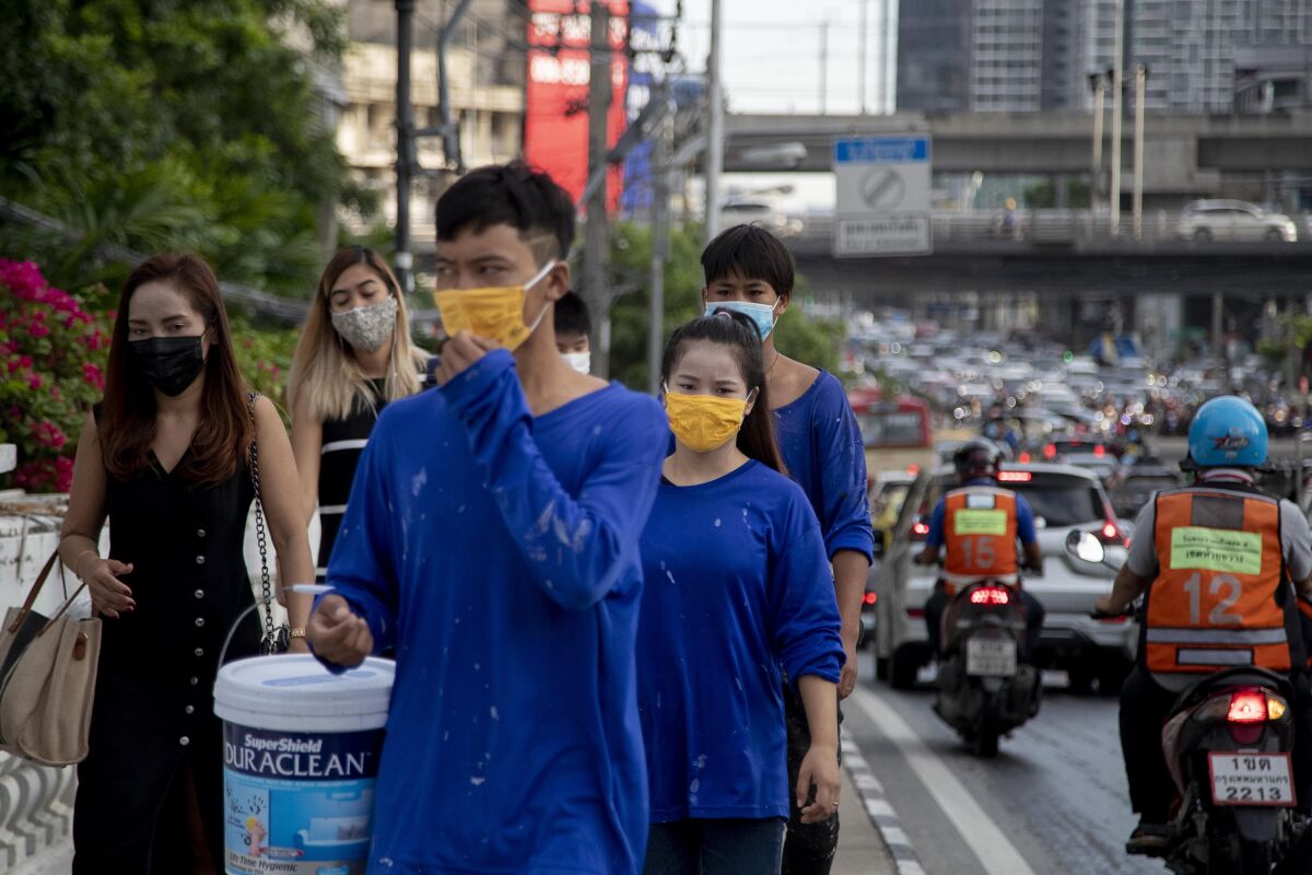 Office workers and construction workers with face masks walk in a side walk in Bangkok, Thailand, Thursday, Sept. 3, 2020. Thailand's prime minister on Wednesday congratulated his countrymen on the nation having achieved 100 days without a new confirmed locally transmitted case of the coronavirus, even as security along the border with Myanmar is being stepped up as a measure against the disease. (AP Photo/ Gemunu Amarasinghe)