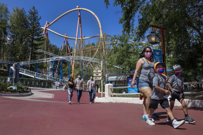 VALENCIA, CA - APRIL 02, 2021:Diana Navarro, 27, of Baldwin Park, and her sons, Moises, 7, left, and Mason, 6, make their way inside Six Flags Magic Mountain in Valencia that re-opened after more than a year of being closed due to the coronavirus outbreak. (Mel Melcon / Los Angeles Times)