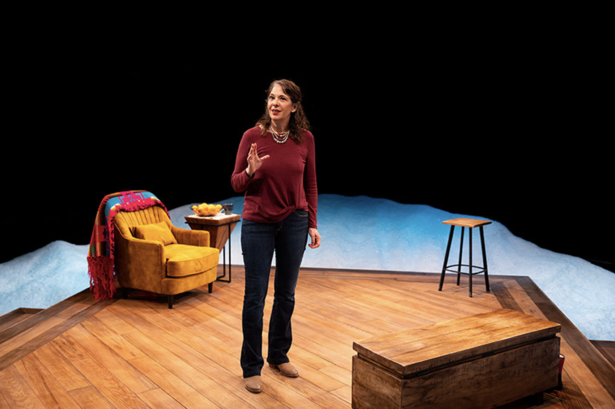 An actor onstage with a lounge chair behind her