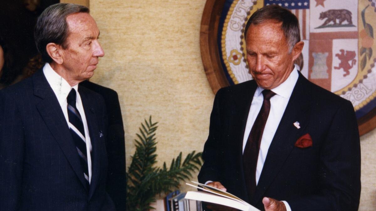 Warren Christopher, left, hands a copy of the Christopher Commission report to then-LAPD Chief Daryl F. Gates. (Rick Meyer / Los Angeles Times)