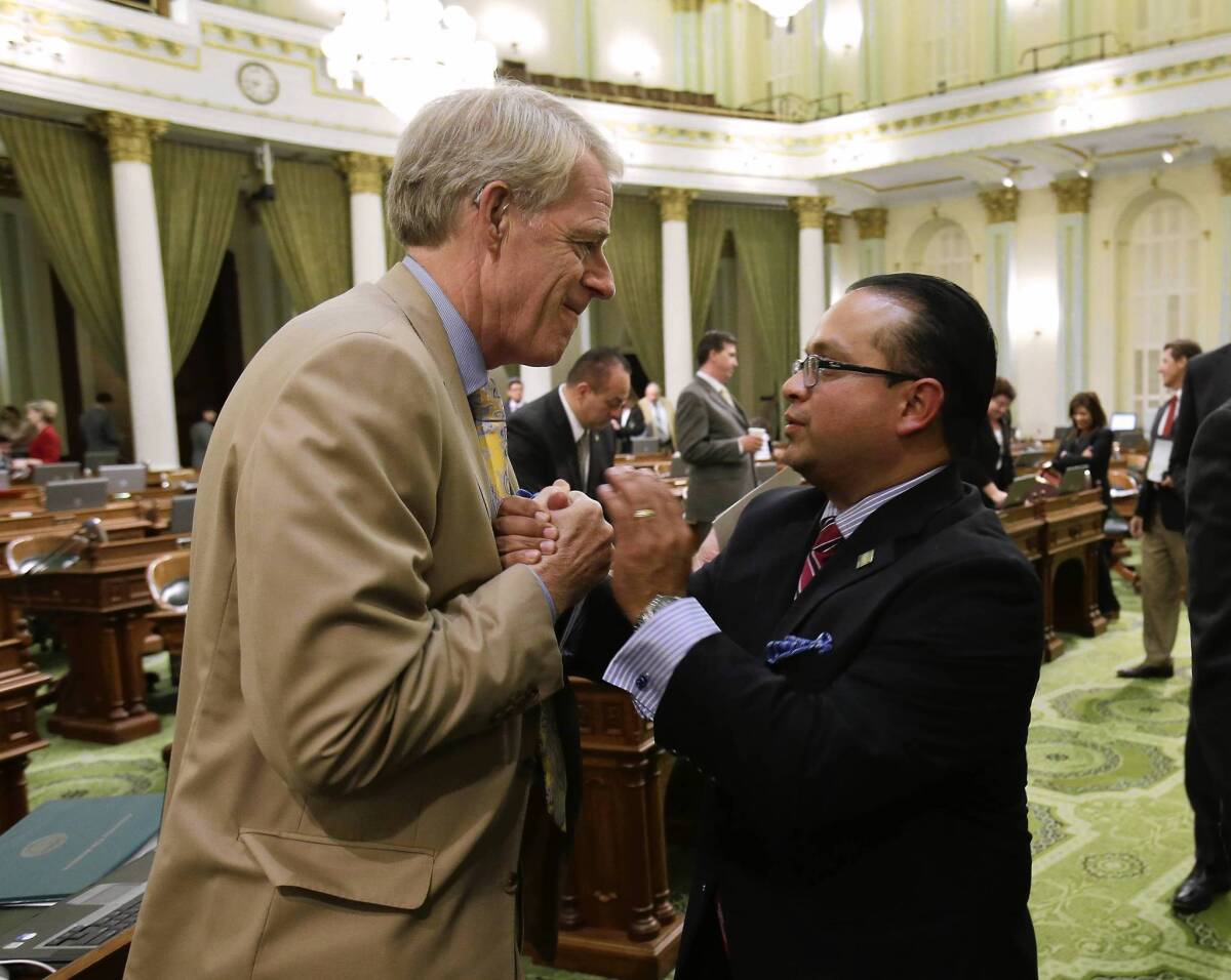 Assemblyman Luis Alejo (D-Watsonville), right, is congratulated by Assemblyman Roger Dickinson (D-Sacramento) after the Assembly approved Alejo's minimum wage bill.