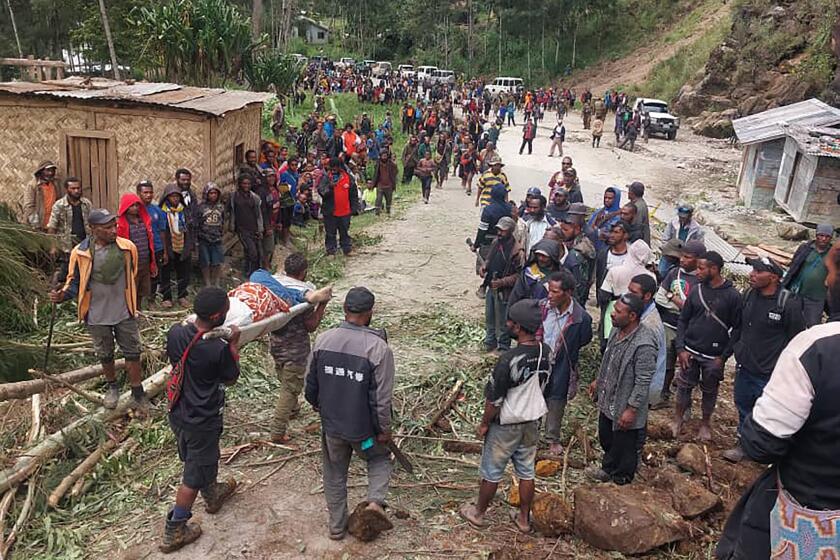 In this photo provides the International Organization for Migration, an injured person is carried on a stretcher to seek medical assistance after a landslide in Yambali village, Papua New Guinea, Friday, May 24, 2024. More than 100 people are believed to have been killed in the landslide that buried a village and an emergency response is underway, officials in the South Pacific island nation said. The landslide struck Enga province, about 600 kilometers (370 miles) northwest of the capital, Port Moresby, at roughly 3 a.m., Australian Broadcasting Corp. reported. (Benjamin Sipa/International Organization for Migration via AP)