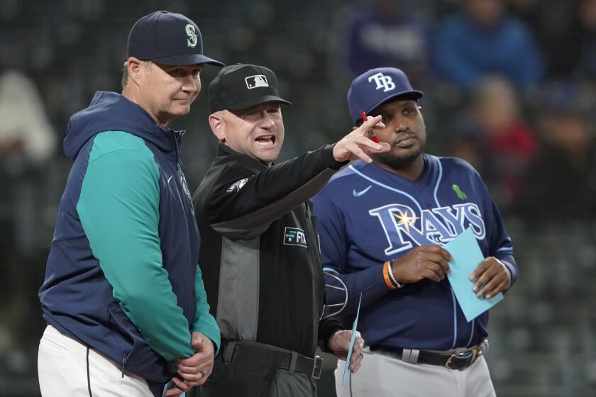 Home plate umpire Mike Muchlinski, center, talks with Seattle Mariners manager Scott Servais.