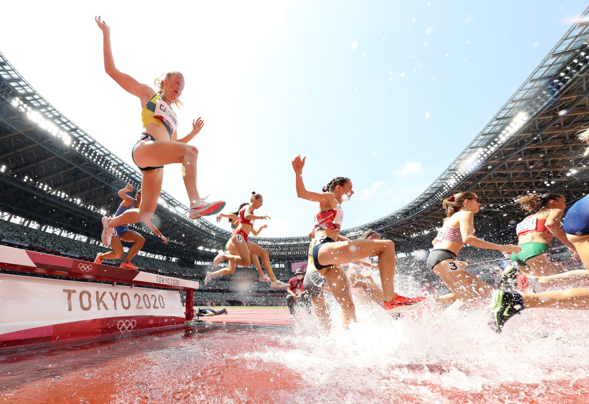 Women leap and run through shallow water.