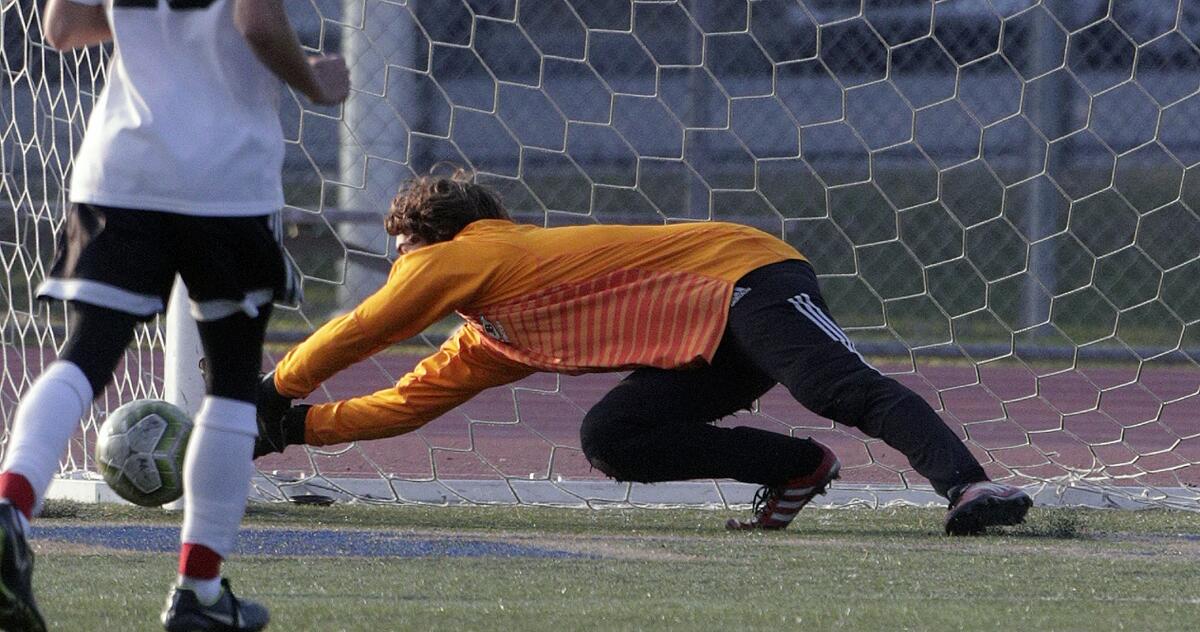 Burroughs' goalie Hyatt Entz dives and keeps a Muir shot from scoring in a Pacific League boys' soccer game at Muir High School in Pasadena on Tuesday, January 14, 2020.