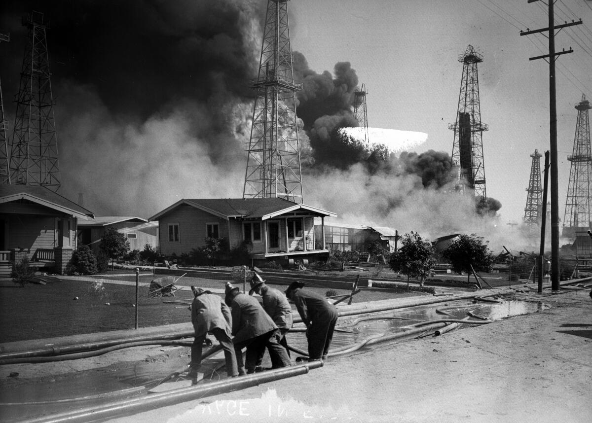 Firefighters lay hoses to protect homes from an oil well fire in Santa Fe Springs in 1928. 